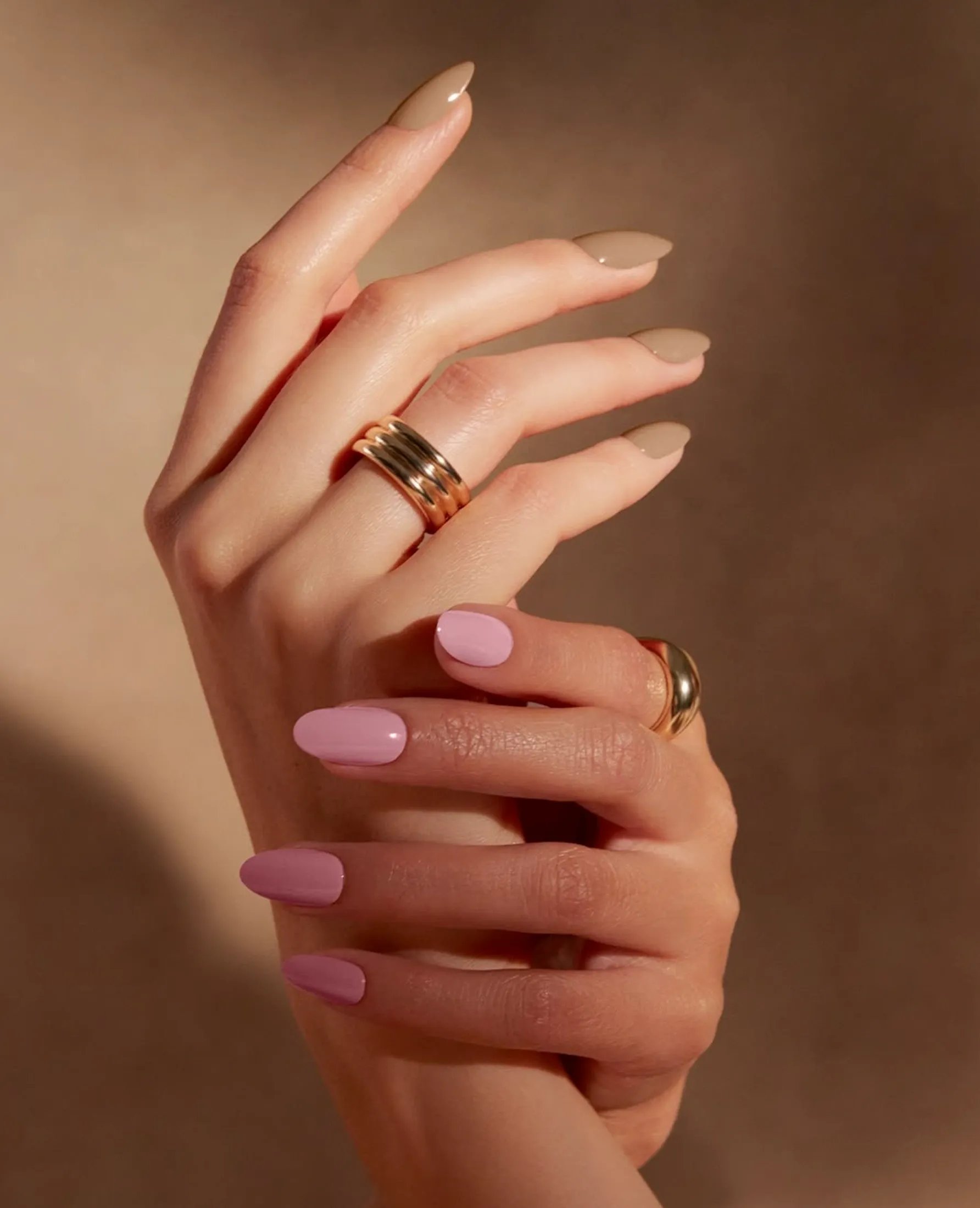 Hands with soft pink and nude manicures and gold rings