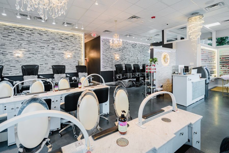 Manicure stations along a pale stone wall, with the reception desk and polish wall beyond