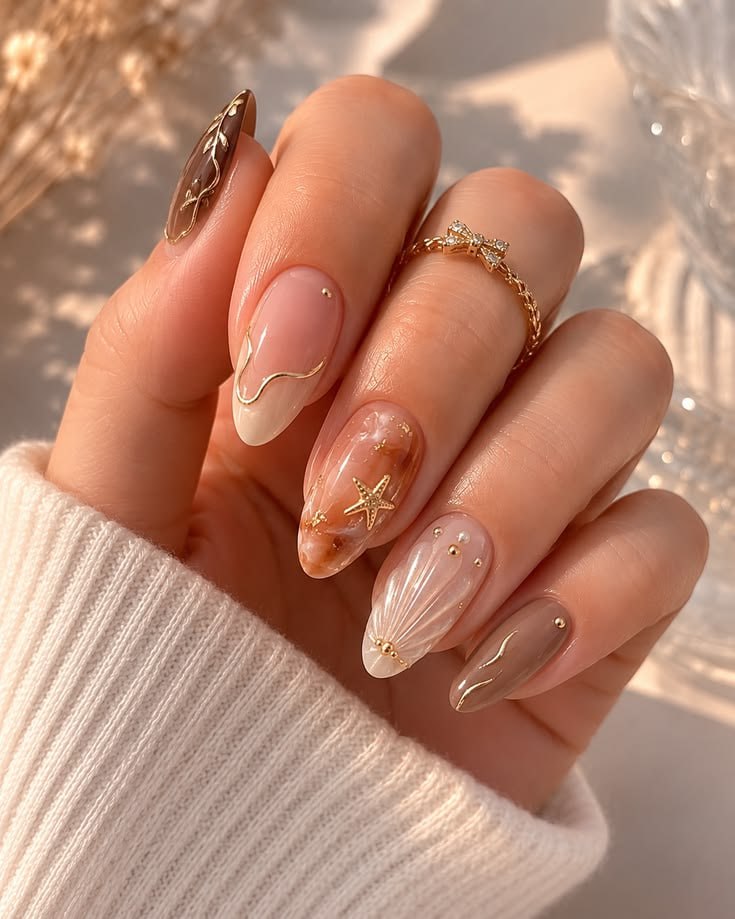 Nude almond nails with gold accents, marble and shell detail
