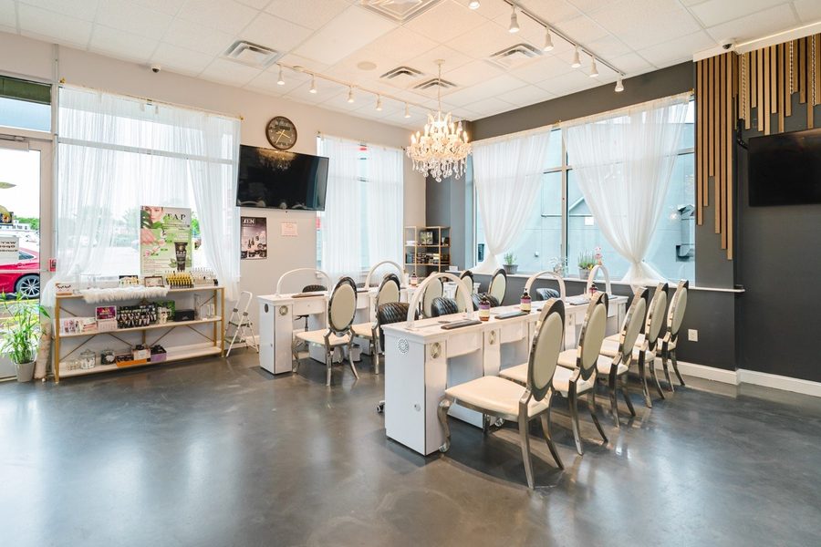 Manicure tables beside the front windows, with sheer curtains and retail shelving