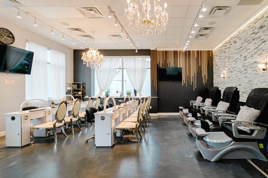 A row of manicure tables facing the pedicure chairs under crystal chandeliers